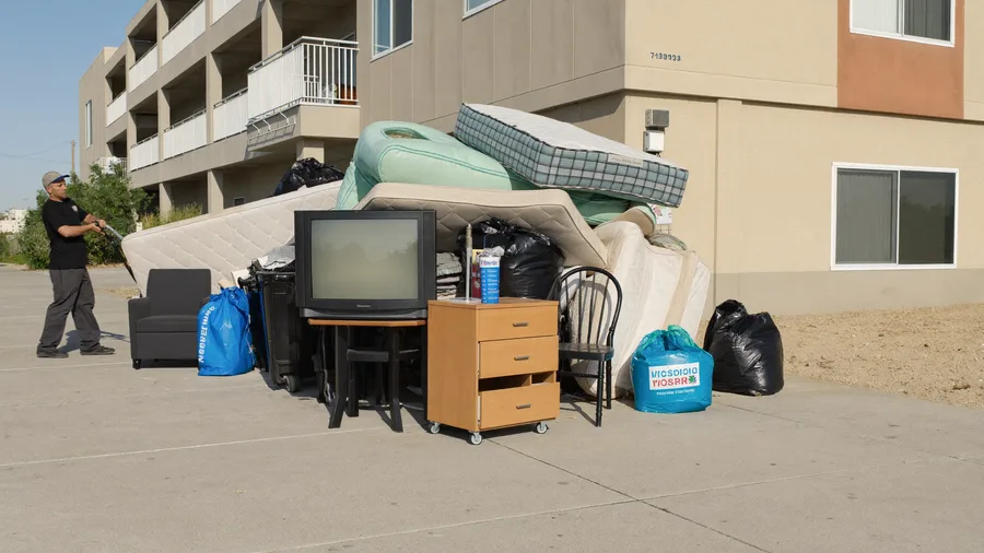Pile of left-behind belongings outside an apartment being loaded onto a hand truck
