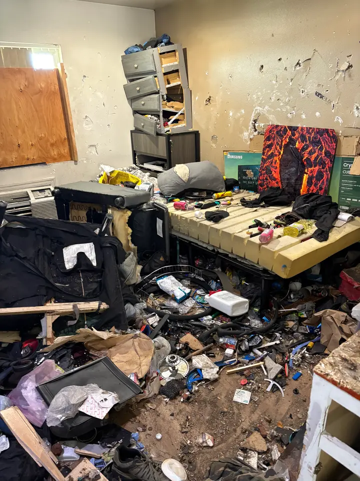 Cluttered bedroom with debris covering the floor before a judgment-free cleanout