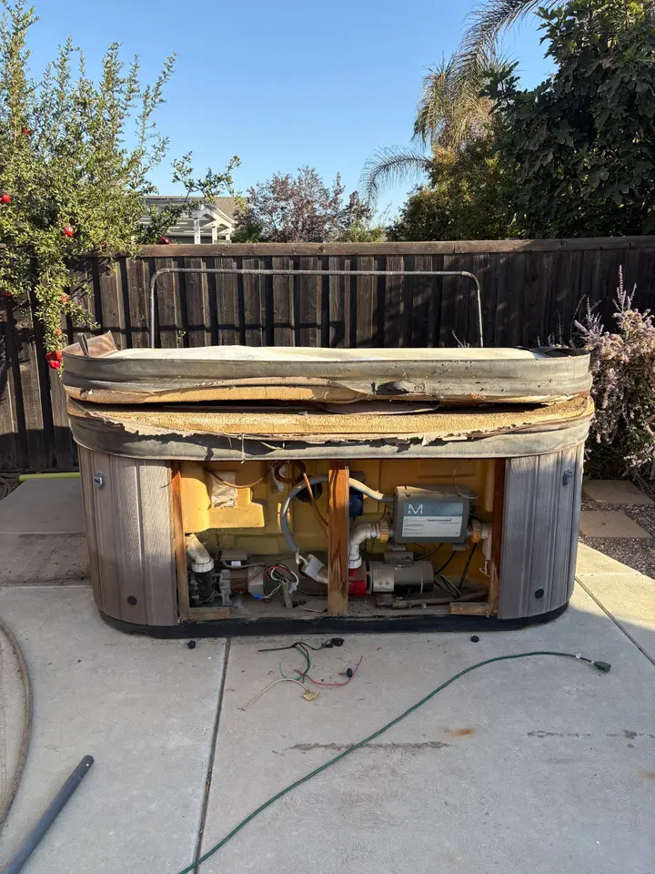Old broken hot tub on a Fresno backyard patio before removal