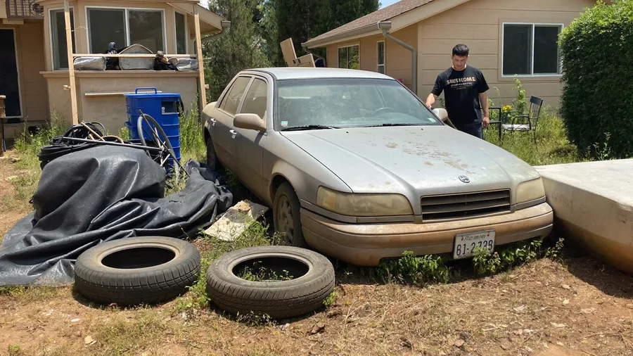 Old abandoned car with flat tires in a dirt side yard