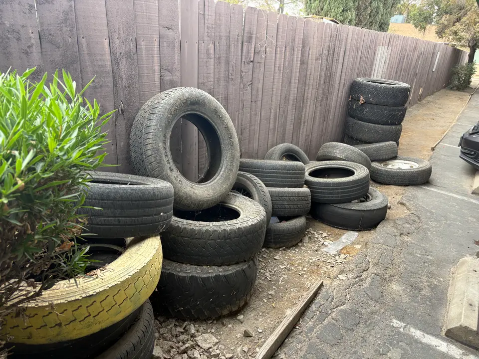 Pile of old tires along a fence before pickup